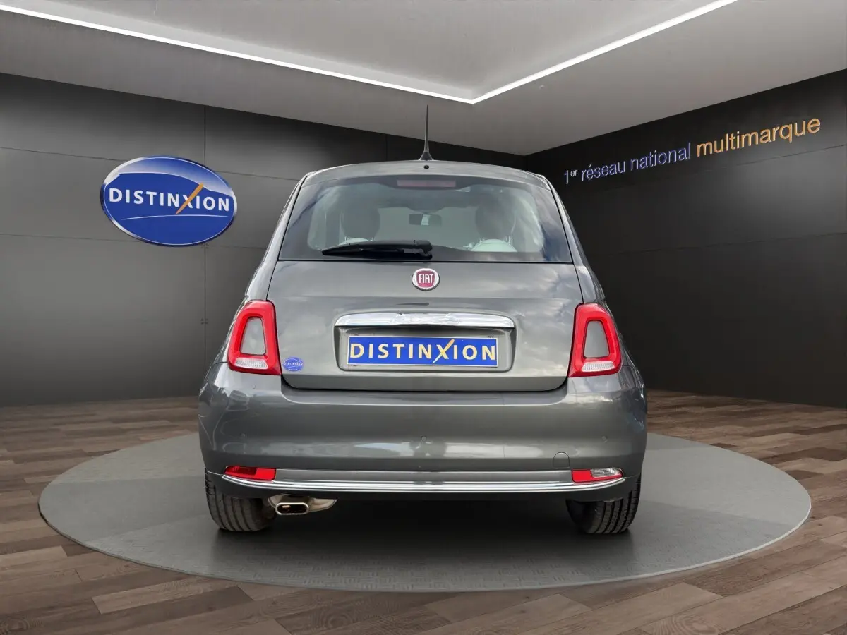 Vue arrière d'une FIAT 500 gris foncé avec feux arrière distinctifs et échappement visible en showroom.