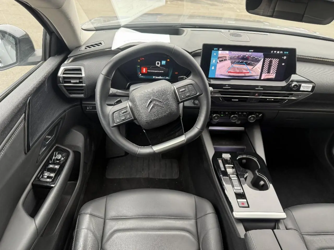 Vue intérieure centrée sur le poste de conduite du Citroën C5 X 2024, avec écran tactile et volant multifonction noir.