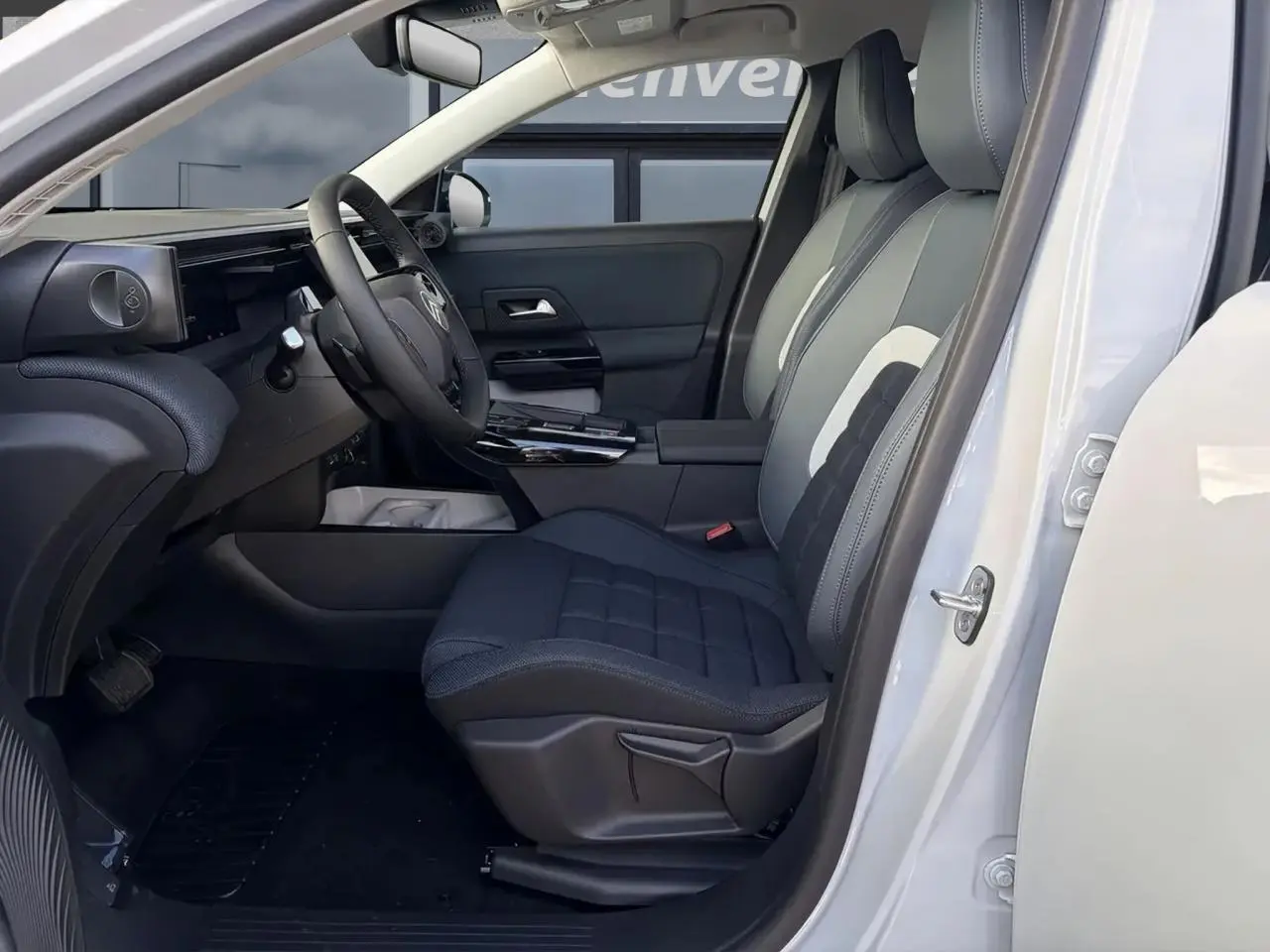 Vue intérieure côté conducteur du Citroën C5 Aircross blanc, montrant sièges tissu bleu et tableau de bord moderne.