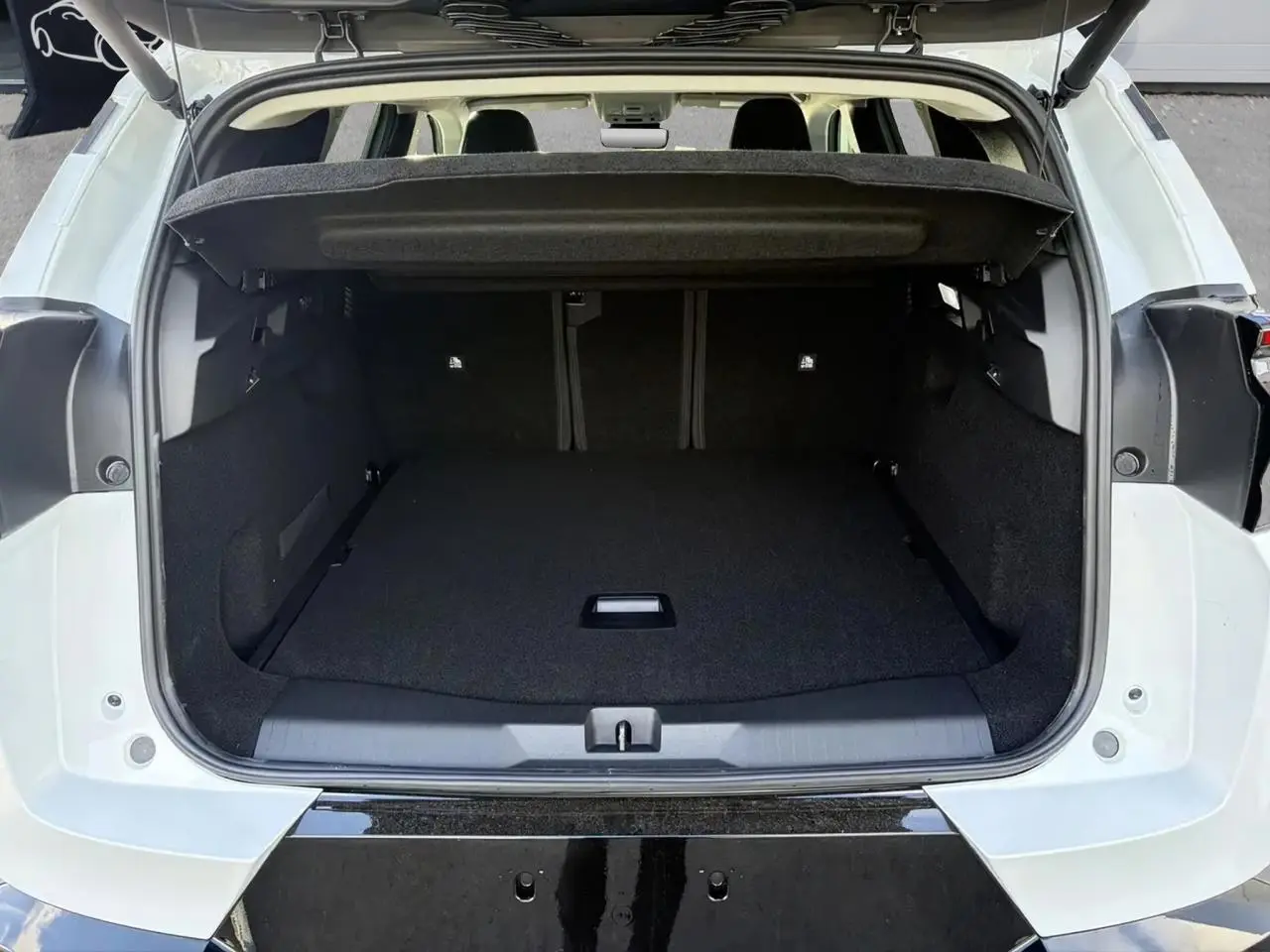 Coffre ouvert vu de l'arrière d'un Citroën C5 Aircross blanc, montrant l'espace de chargement vide et la plage arrière relevée.