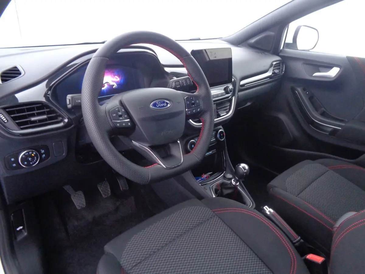 Intérieur avant droit du Ford Puma 2022, volant cuir noir avec surpiqûres rouges et console centrale moderne.