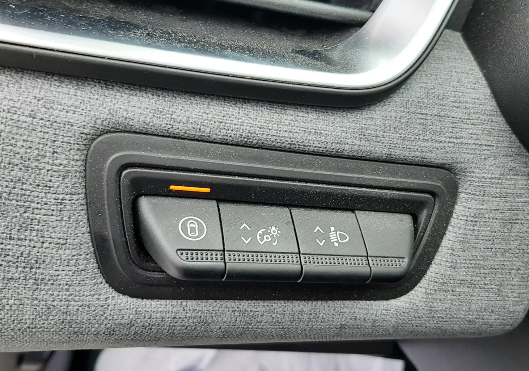 Gros plan sur les commandes de réglage d'éclairage et verrouillage sur tableau de bord gris tissu d'une Renault Clio V gris schiste.