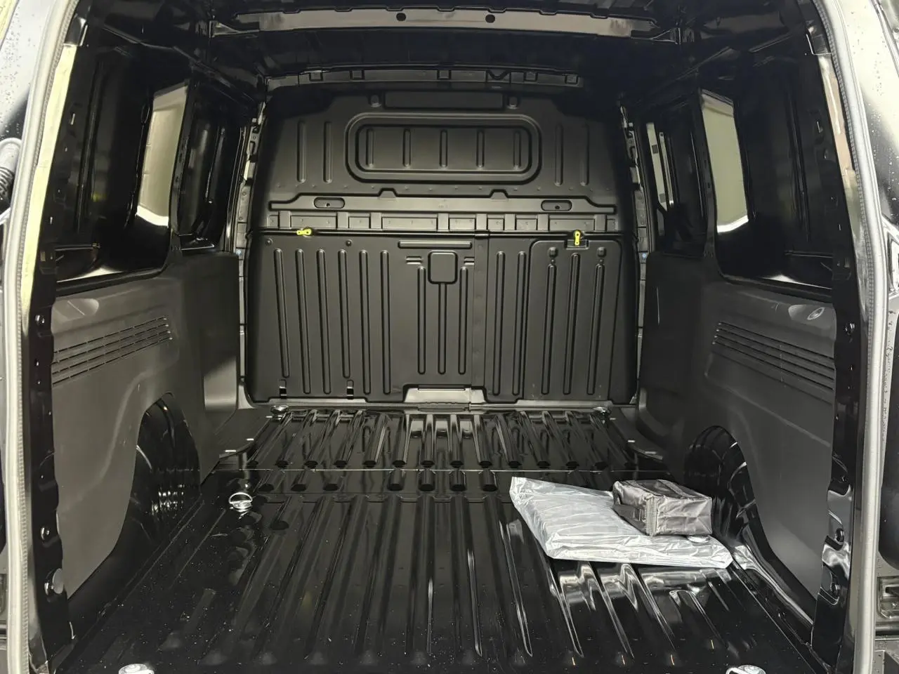 Intérieur noir Perla du coffre du Citroën Berlingo Van XL 2025, vue de l'arrière avec rangement au sol visible.