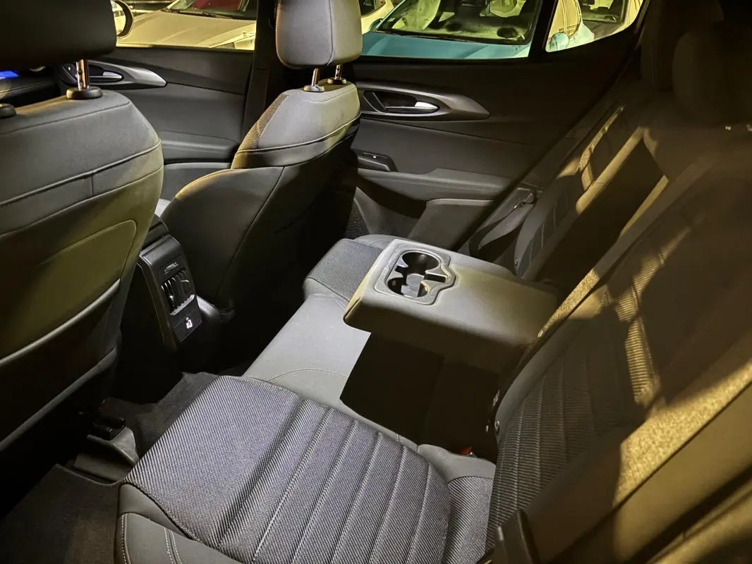 Vue intérieure arrière côté droit de l'Alfa Romeo Tonale 1.3 hybride, sièges noirs avec accoudoir central et porte-gobelets.