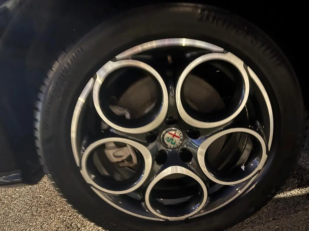 Gros plan sur la jante alliage 18 pouces noire et argentée de l'Alfa Romeo Tonale gris, avec logo au centre.