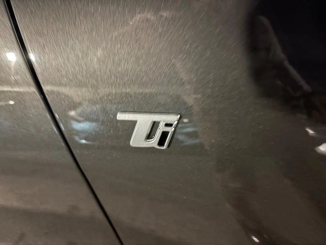 Gros plan sur l’écusson Ti argenté sur la porte grise métallisée de l’Alfa Romeo Tonale 2023.