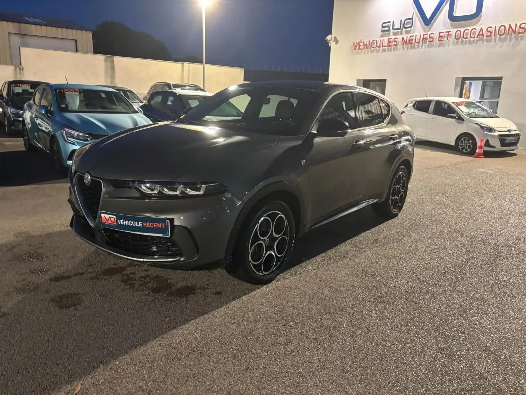 Vue 3/4 avant d'une Alfa Romeo Tonale gris métallisé avec jantes alliage 18 pouces, stationnée de nuit en extérieur.