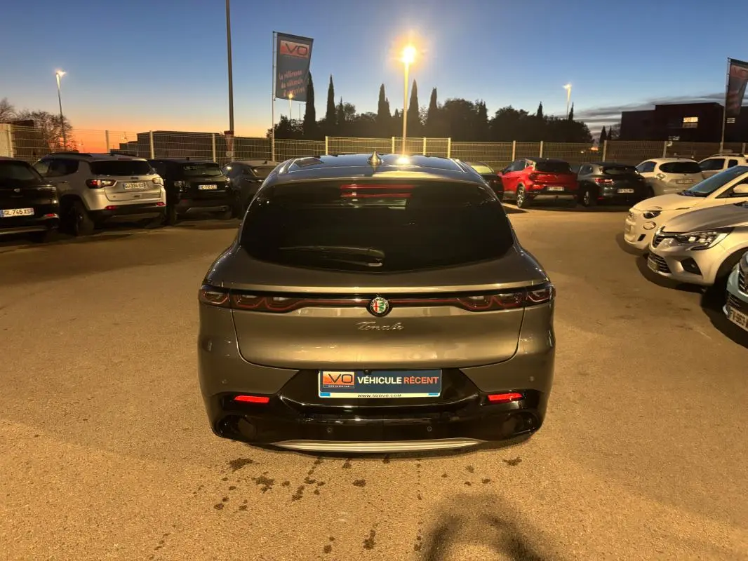Vue arrière d'une Alfa Romeo Tonale gris métallisé 2023 avec feux LED et logo centré au crépuscule.