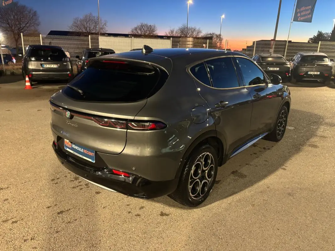 Vue 3/4 arrière droite d'une Alfa Romeo Tonale gris métallisé 2023 avec jantes alliage 18 pouces, en extérieur au crépuscule.