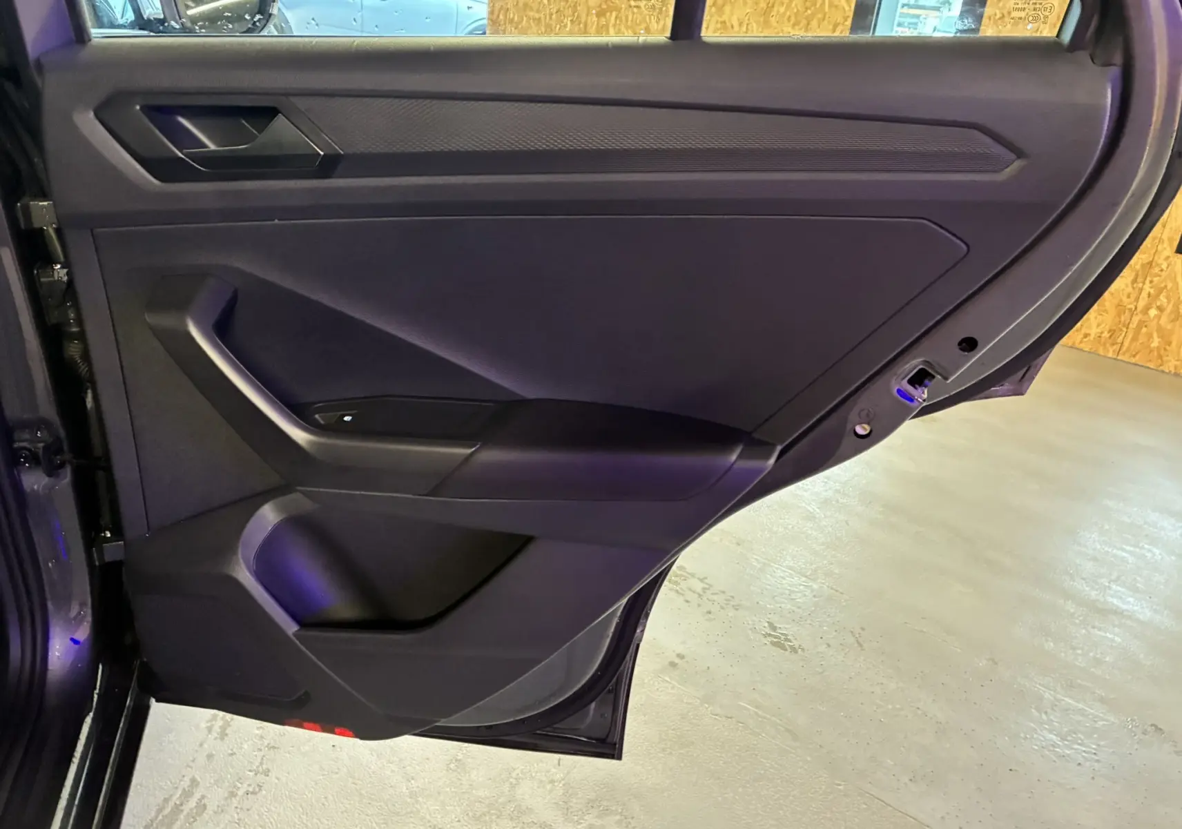 Vue intérieure de la porte arrière droite gris foncé du Volkswagen T-Roc 2023 avec poignée intégrée et panneau épuré.