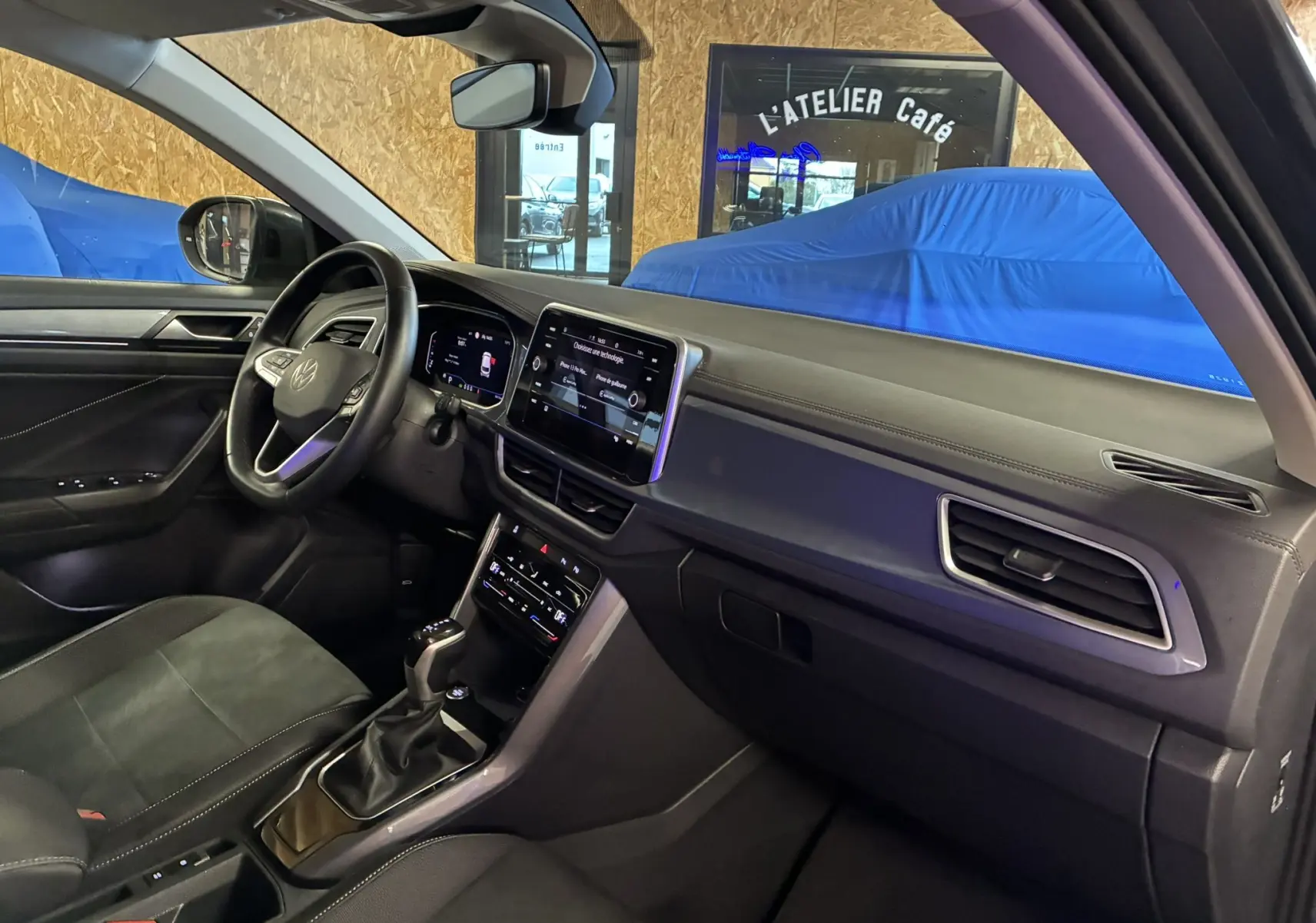 Vue intérieure côté conducteur du Volkswagen T-Roc gris 2023, mettant en valeur le tableau de bord digital et la console centrale moderne.
