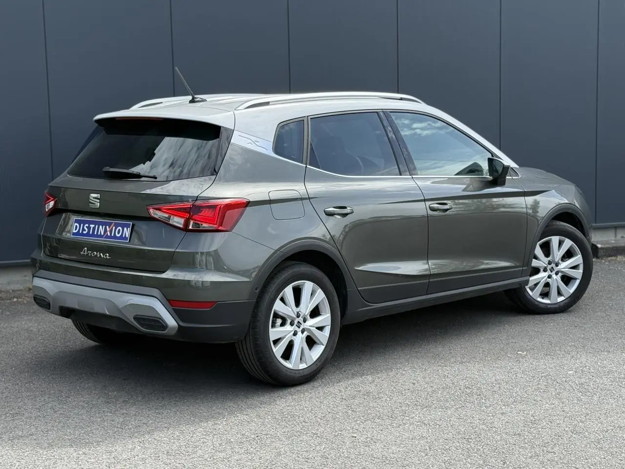 Vue 3/4 arrière droite d'un SEAT Arona gris Cliff avec toit blanc et jantes alliage 17 pouces.