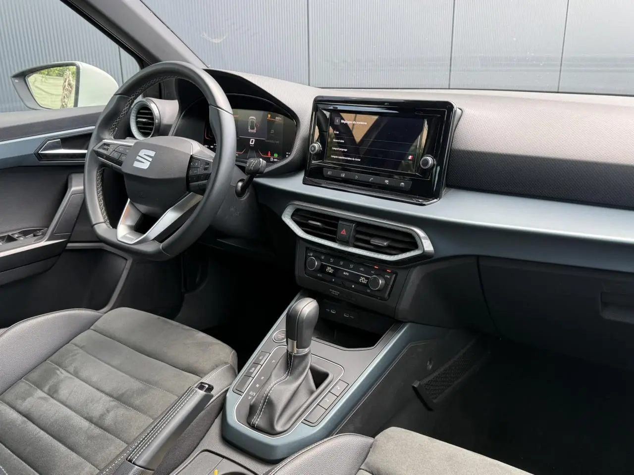 Vue intérieure côté conducteur du SEAT Arona gris Cliff 2025, avec tableau de bord digital et console centrale moderne.