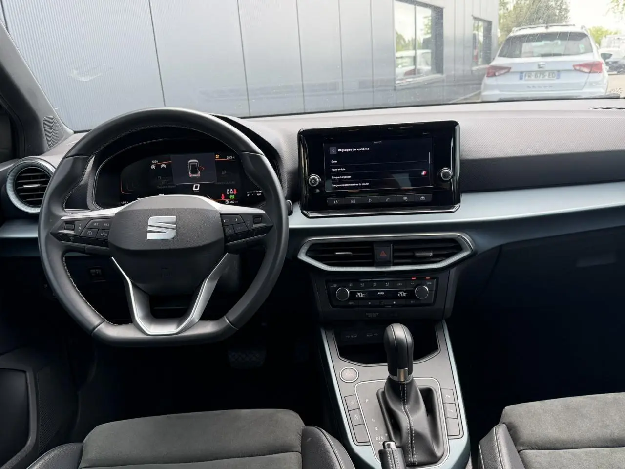 Vue intérieure avant du SEAT Arona 2025 avec tableau de bord noir, volant multifonction et écran tactile central.