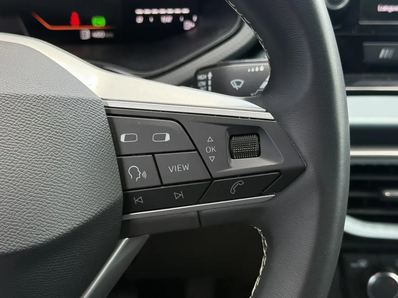 Gros plan sur la partie droite du volant noir du SEAT Arona 2025 avec commandes multifonctions et combiné digital en arrière-plan.