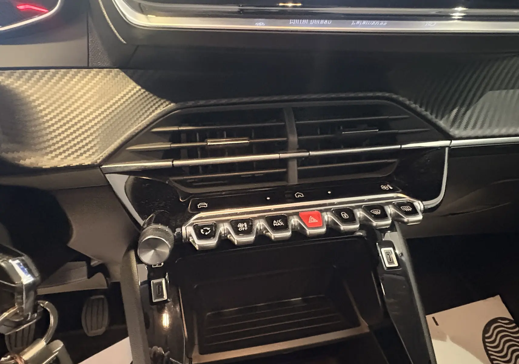 Vue rapprochée du tableau de bord de la Peugeot 208 Active 2024, mettant en valeur les commandes et la finition carbone noire.