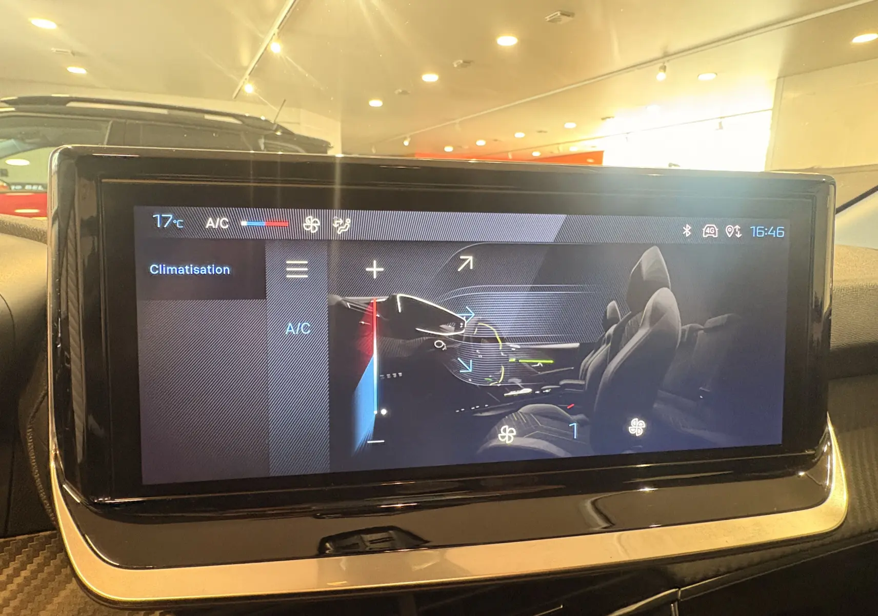 Écran tactile central affichant le réglage de la climatisation dans une Peugeot 208 rouge, vue intérieure.