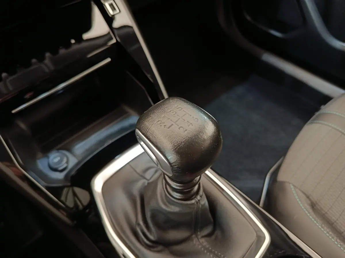 Gros plan sur le levier de vitesses manuel en cuir noir dans l’habitacle d’une Peugeot 2008 bleu.