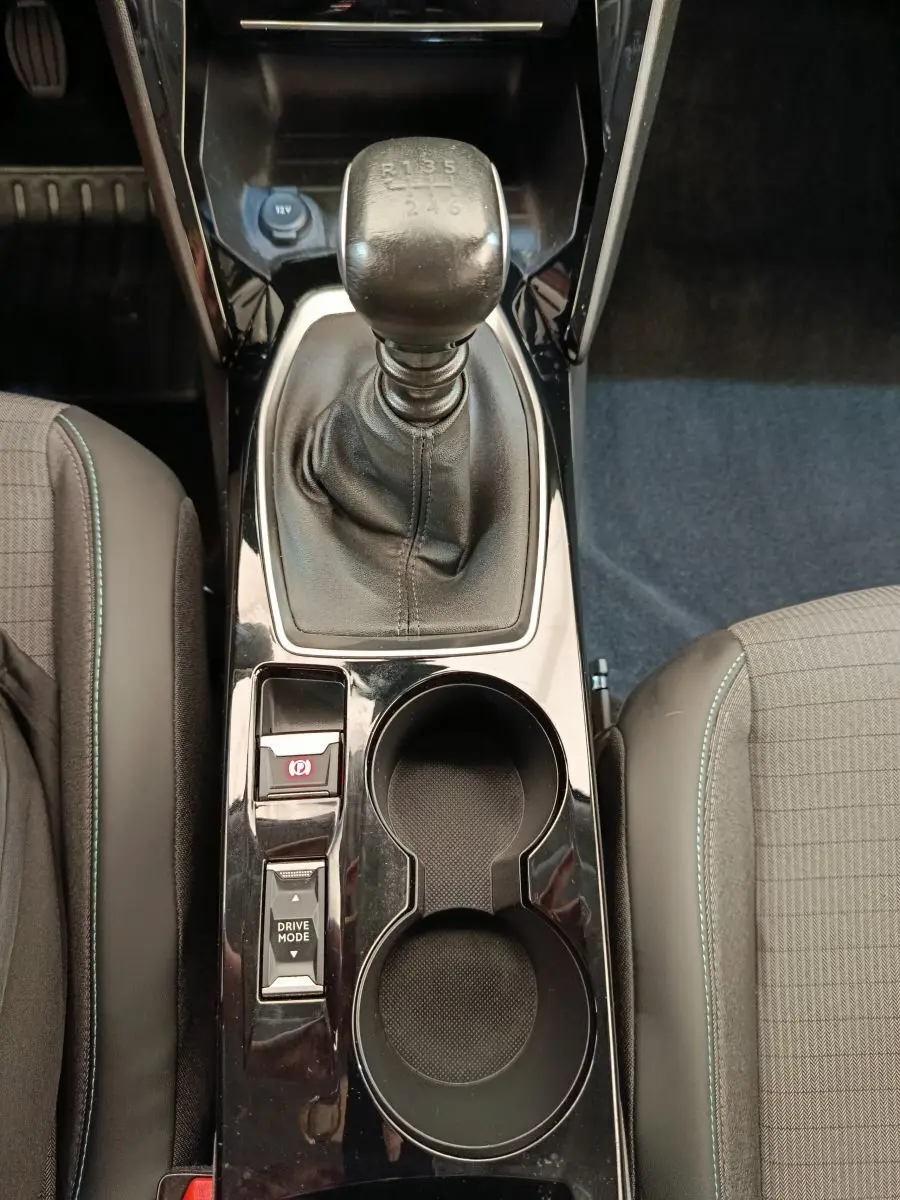 Vue intérieure centrée sur la console centrale noire avec levier de vitesses manuel et porte-gobelets du Peugeot 2008 bleu.