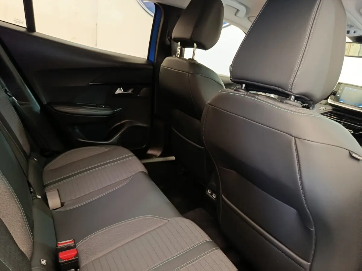 Vue intérieure arrière droite de la Peugeot 2008 bleu, montrant la banquette tissu et cuir avec coutures contrastées.