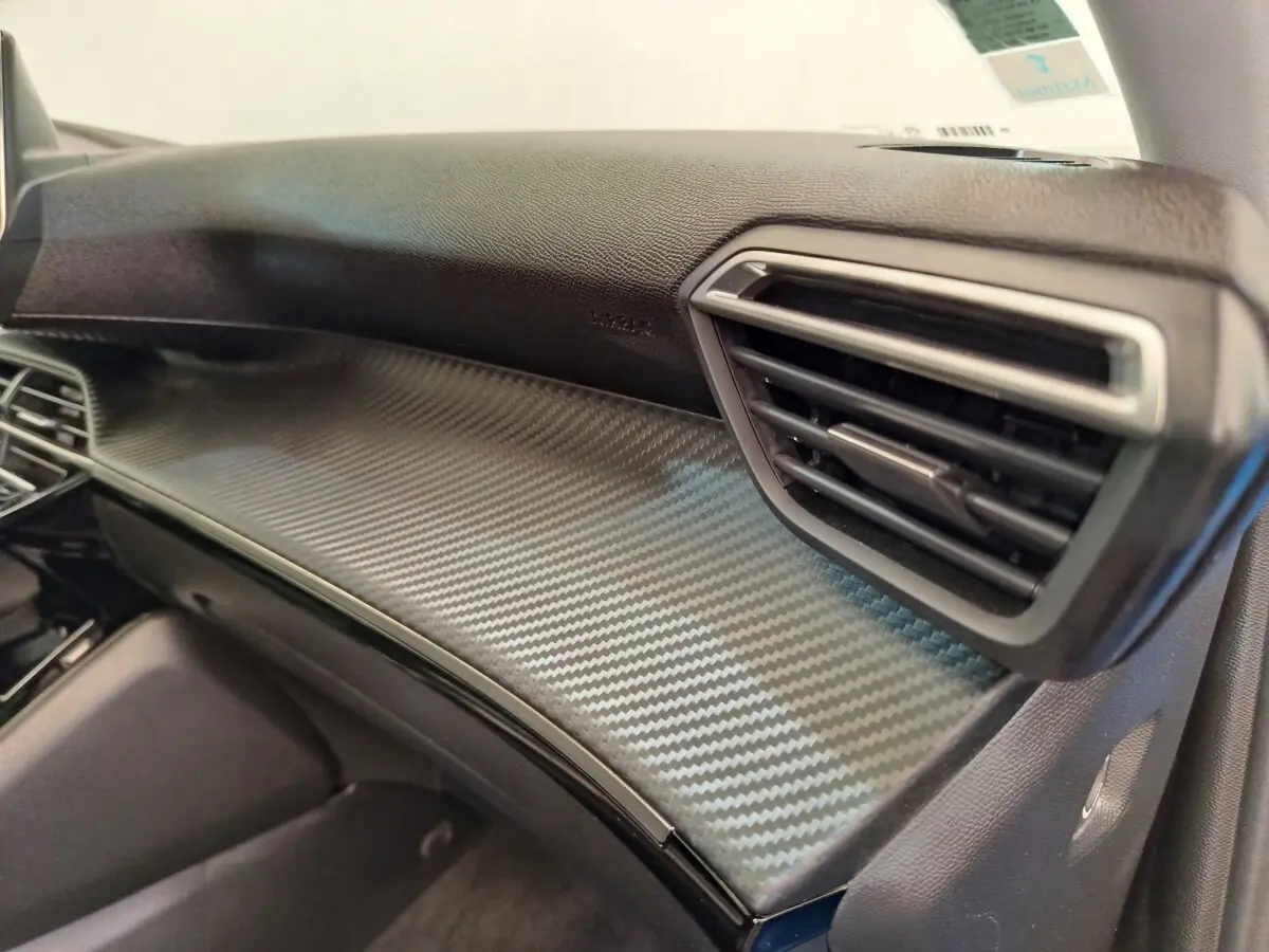 Détail intérieur côté passager du tableau de bord en finition carbone du Peugeot 2008 bleu PureTech 2021.
