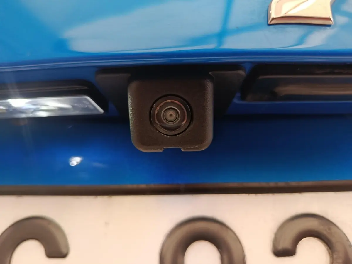 Gros plan sur la caméra de recul noire intégrée au hayon bleu d'une Peugeot 2008 PureTech 100 S&S Allure Pack.