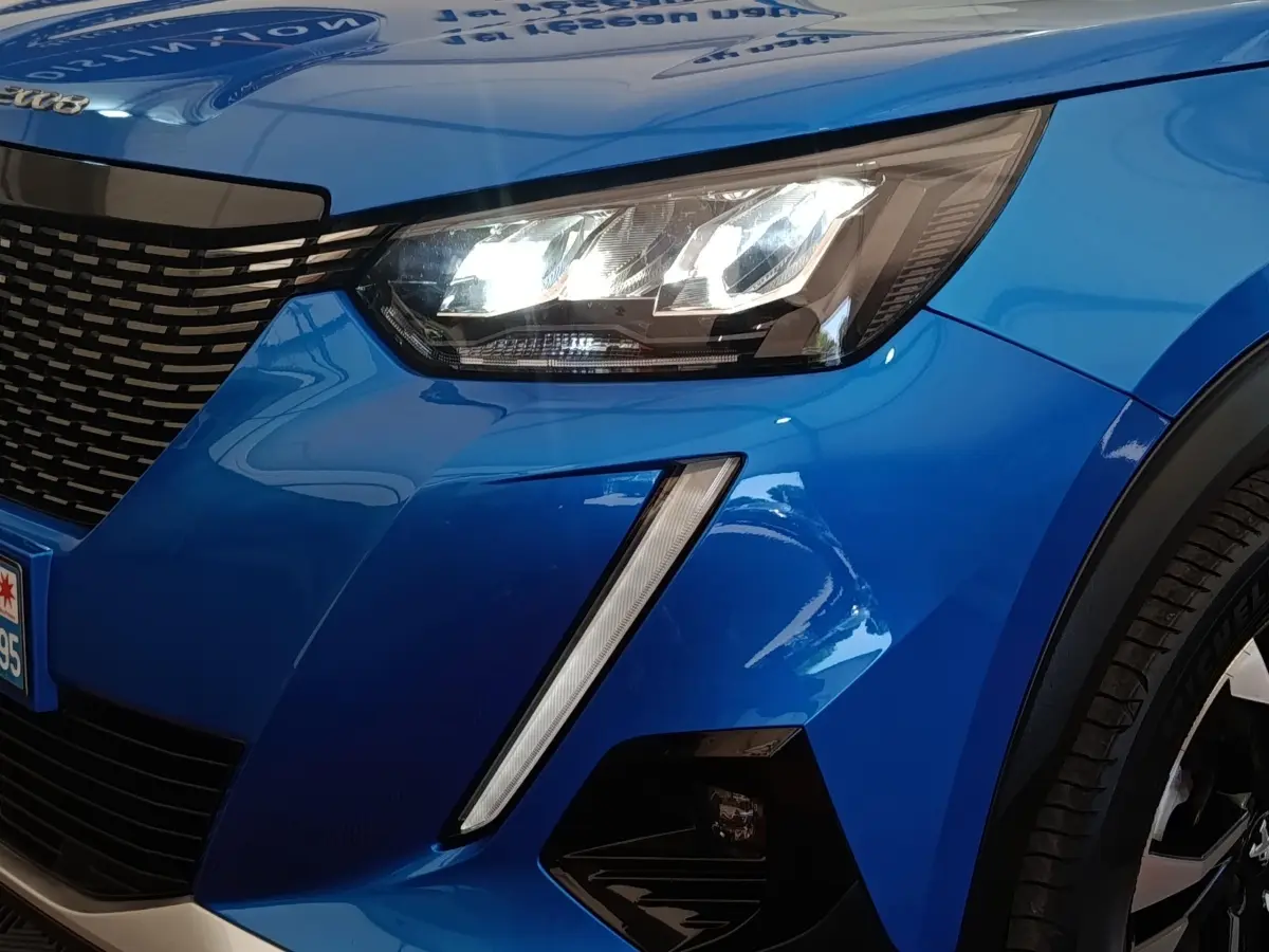 Gros plan sur l'avant droit bleu vif du Peugeot 2008 avec phares LED et calandre noire distinctive.