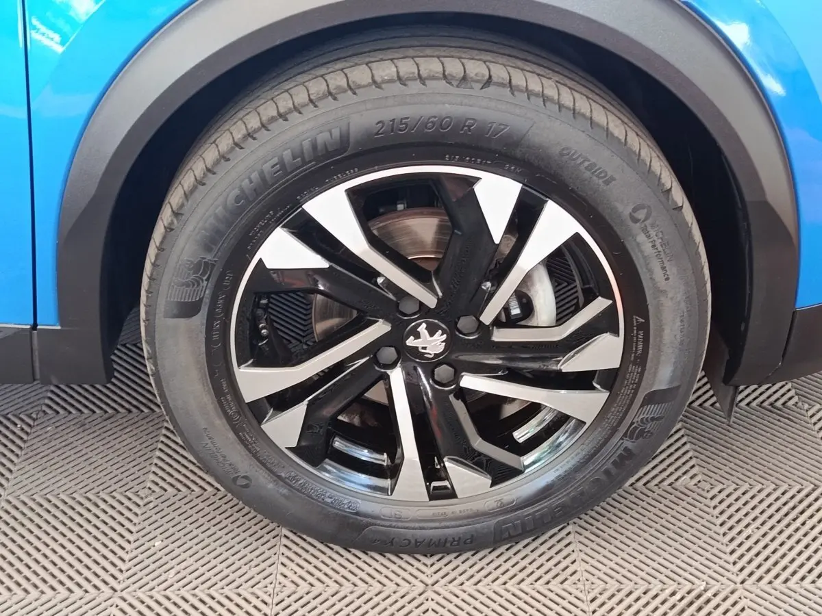 Gros plan sur la roue avant droite noire et argentée du Peugeot 2008 bleu, mettant en valeur la jante au design moderne.