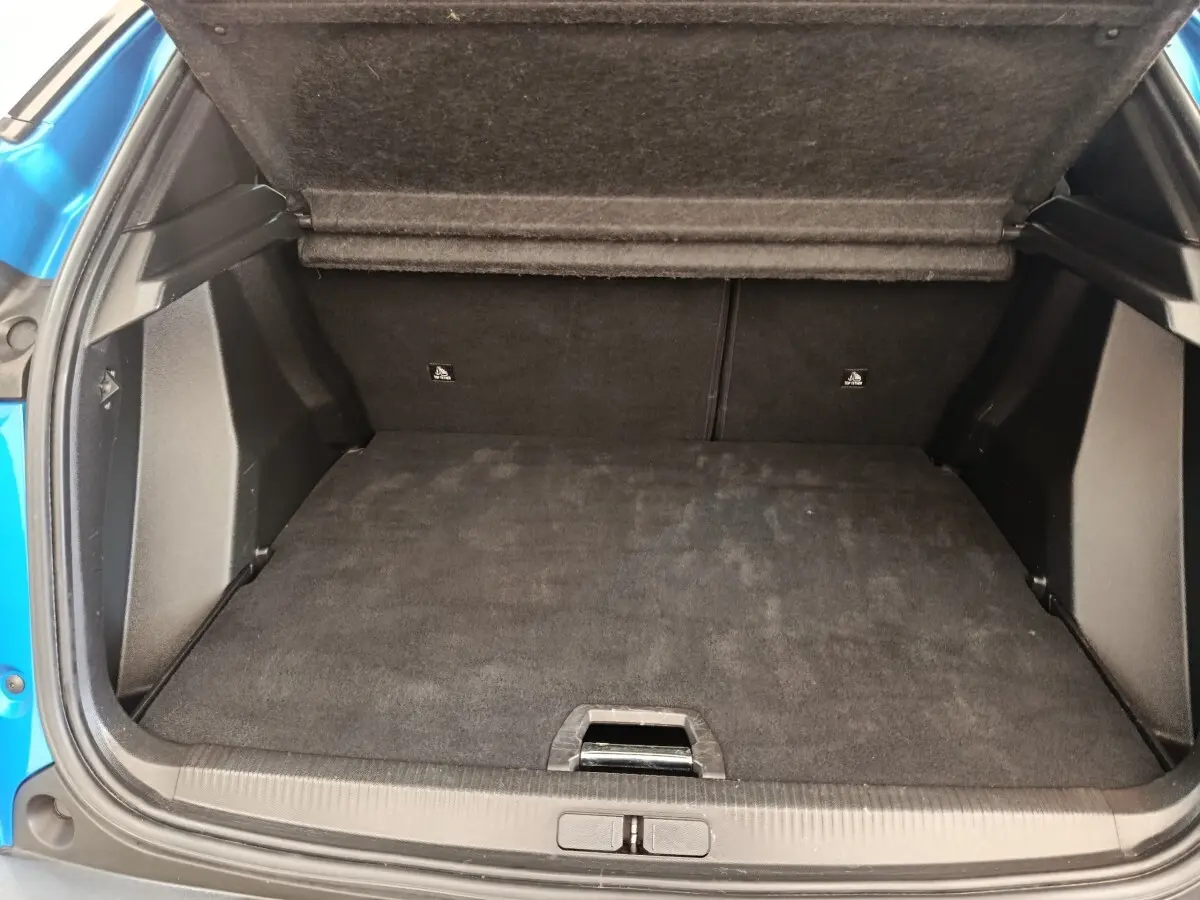 Coffre ouvert de Peugeot 2008 bleu, vue arrière, montrant l'espace de chargement avec plancher plat et banquette rabattue.