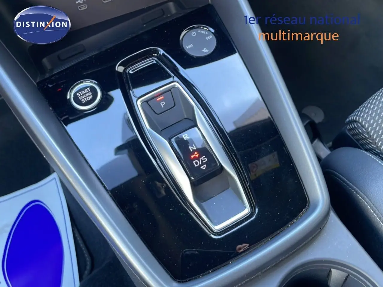 Gros plan sur la console centrale noire brillante de l'Audi A3 Sportback 2025 avec levier de vitesses automatique et bouton start/stop.