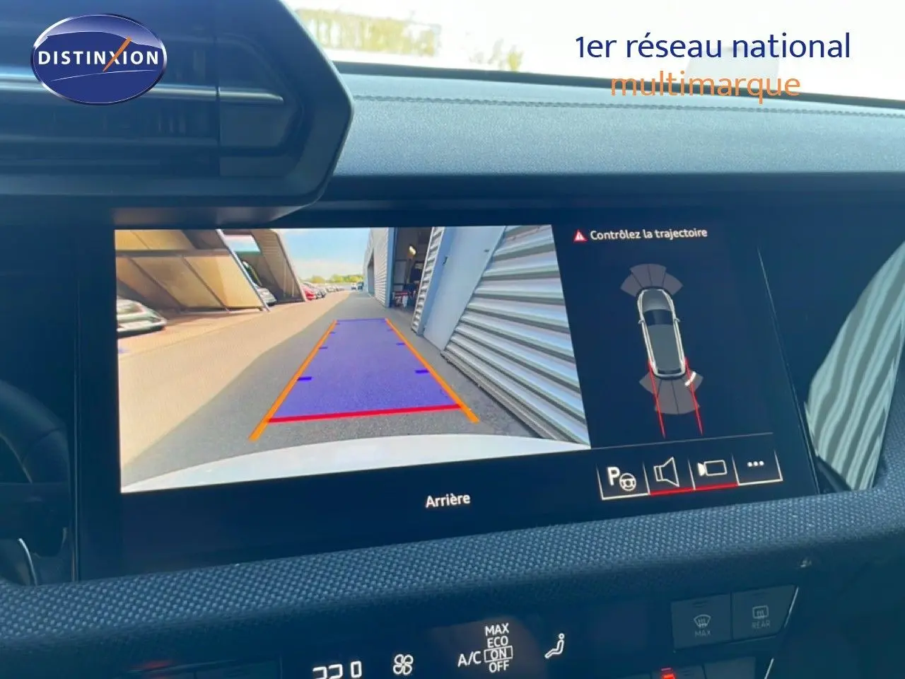 Écran de caméra de recul intérieur d’Audi A3 Sportback blanc Ibis, affichant les lignes de guidage et l’environnement arrière.
