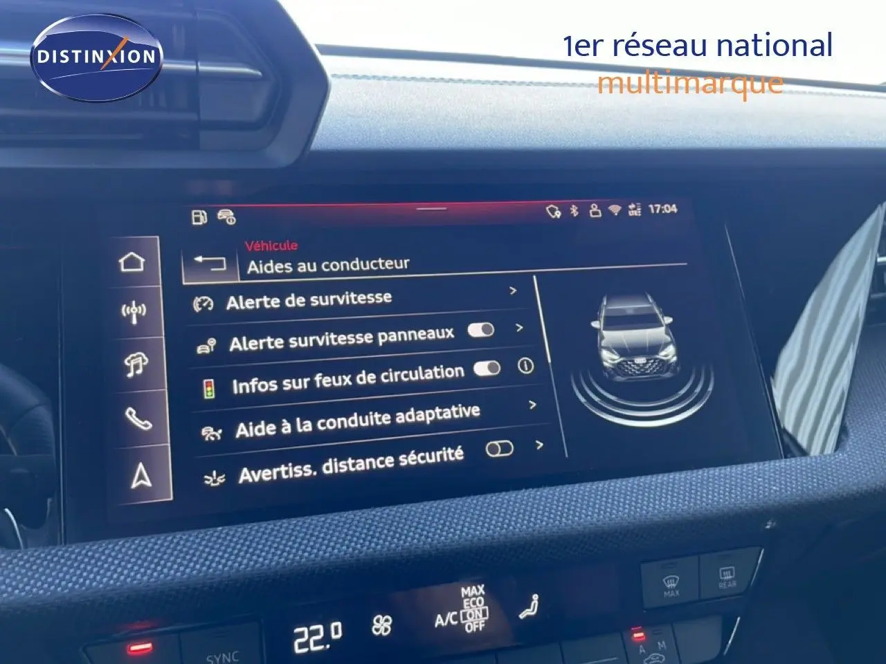 Vue rapprochée de l’écran central du tableau de bord de l’Audi A3 Sportback blanc ibis, affichant les aides à la conduite.