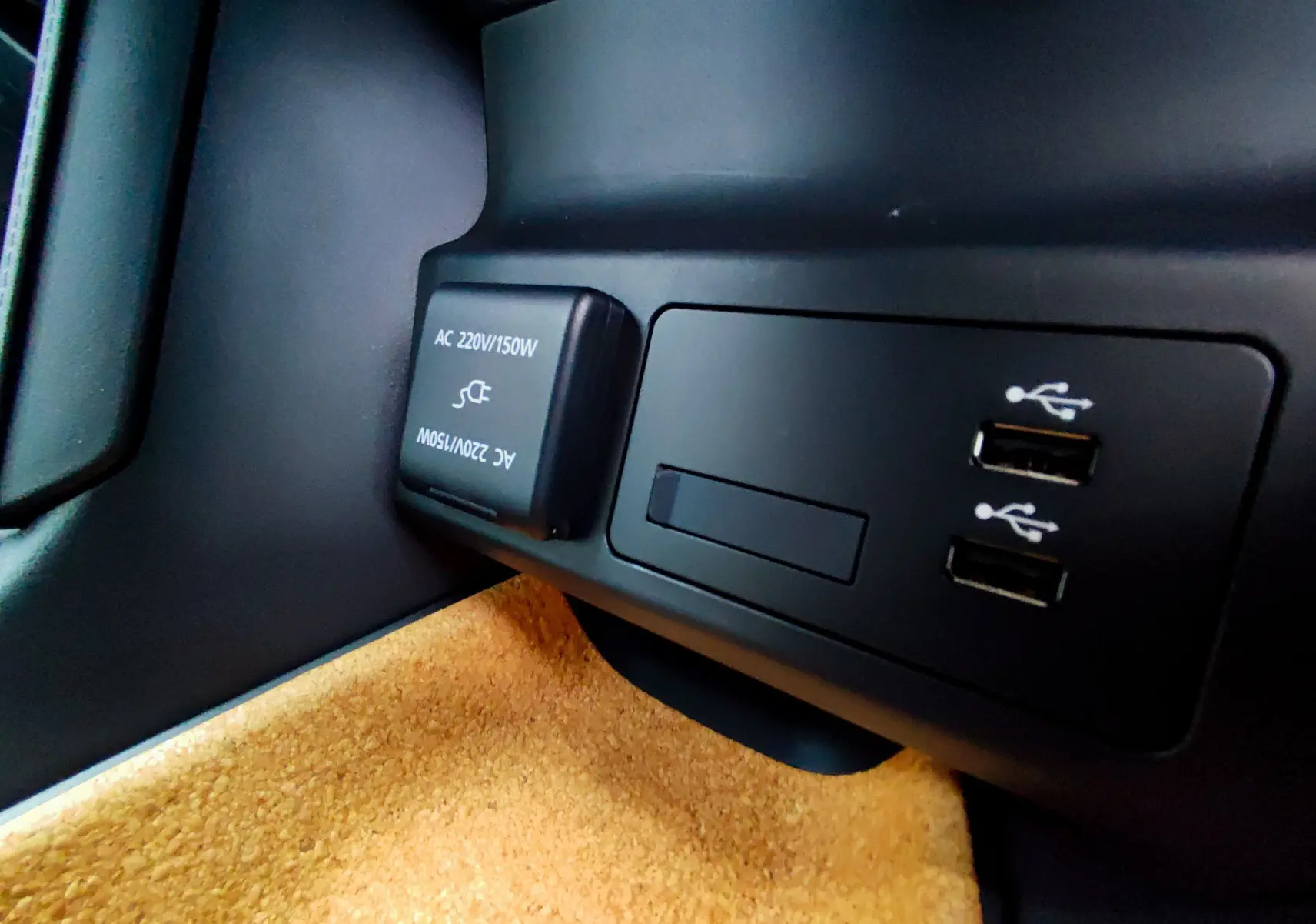 Prise 220V et double port USB en gros plan sur la console intérieure du Mazda MX-30 gris foncé 2023 hybride rechargeable.