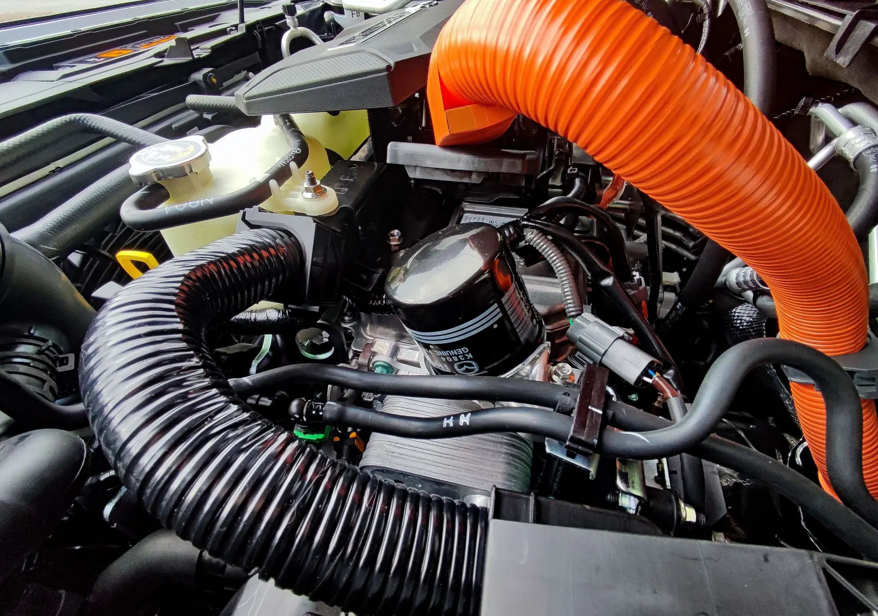 Gros plan sur le moteur hybride rechargeable du Mazda MX-30 2023, avec tuyaux orange et noir visibles.