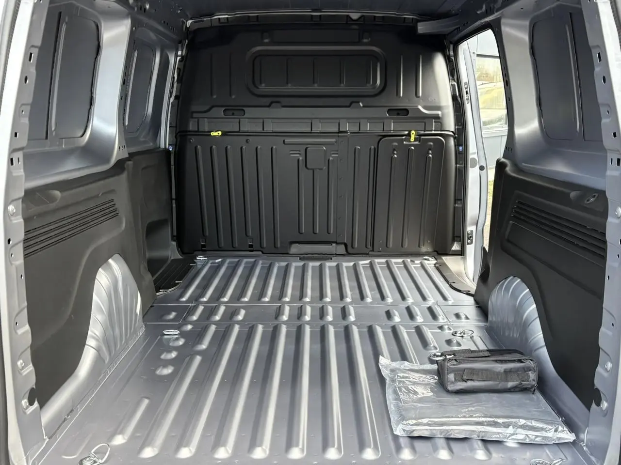 Vue intérieure arrière du Citroën Berlingo Van XL gris Artense montrant l'espace de chargement vide avec un kit posé au sol.