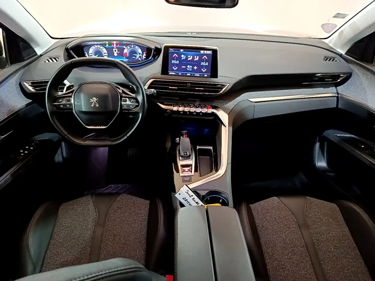 Intérieur du Peugeot 5008 gris clair, vue frontale sur le tableau de bord avec écran tactile et volant compact cuir.