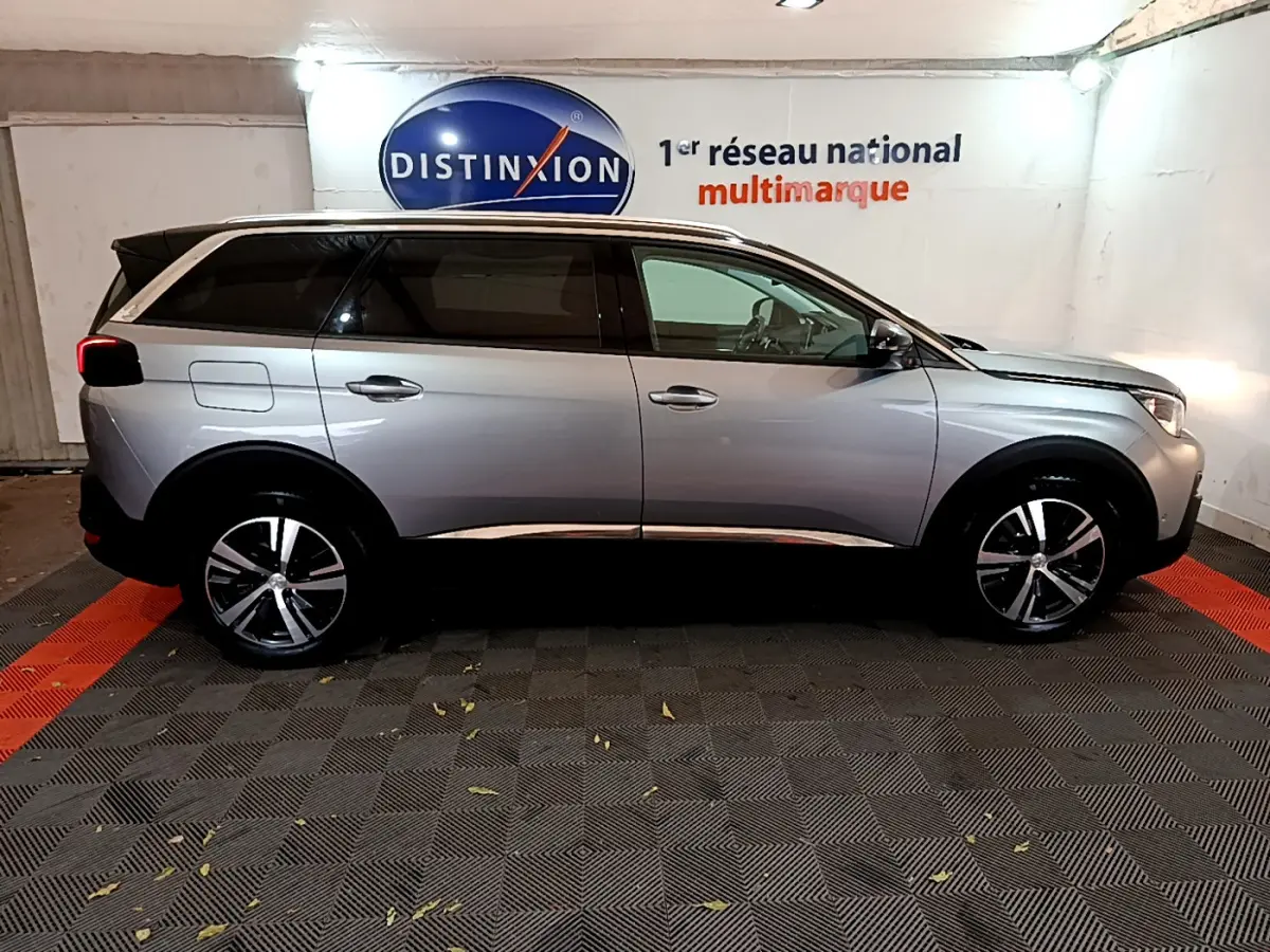Profil droit d'un Peugeot 5008 gris clair 2020, SUV familial avec toit chromé et jantes alliage modernes.
