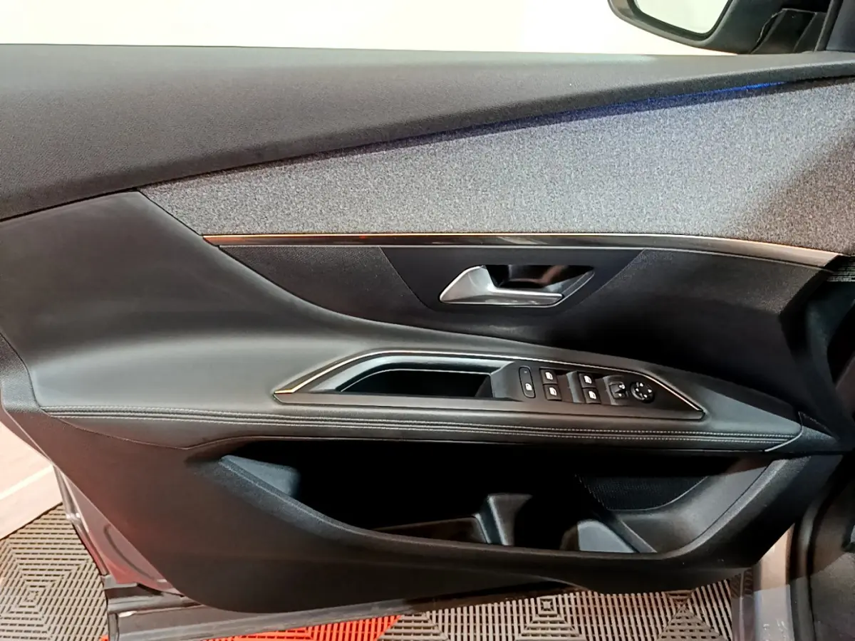 Vue rapprochée de la porte avant gauche du Peugeot 5008 gris clair, avec commandes de vitres et poignée argentée.