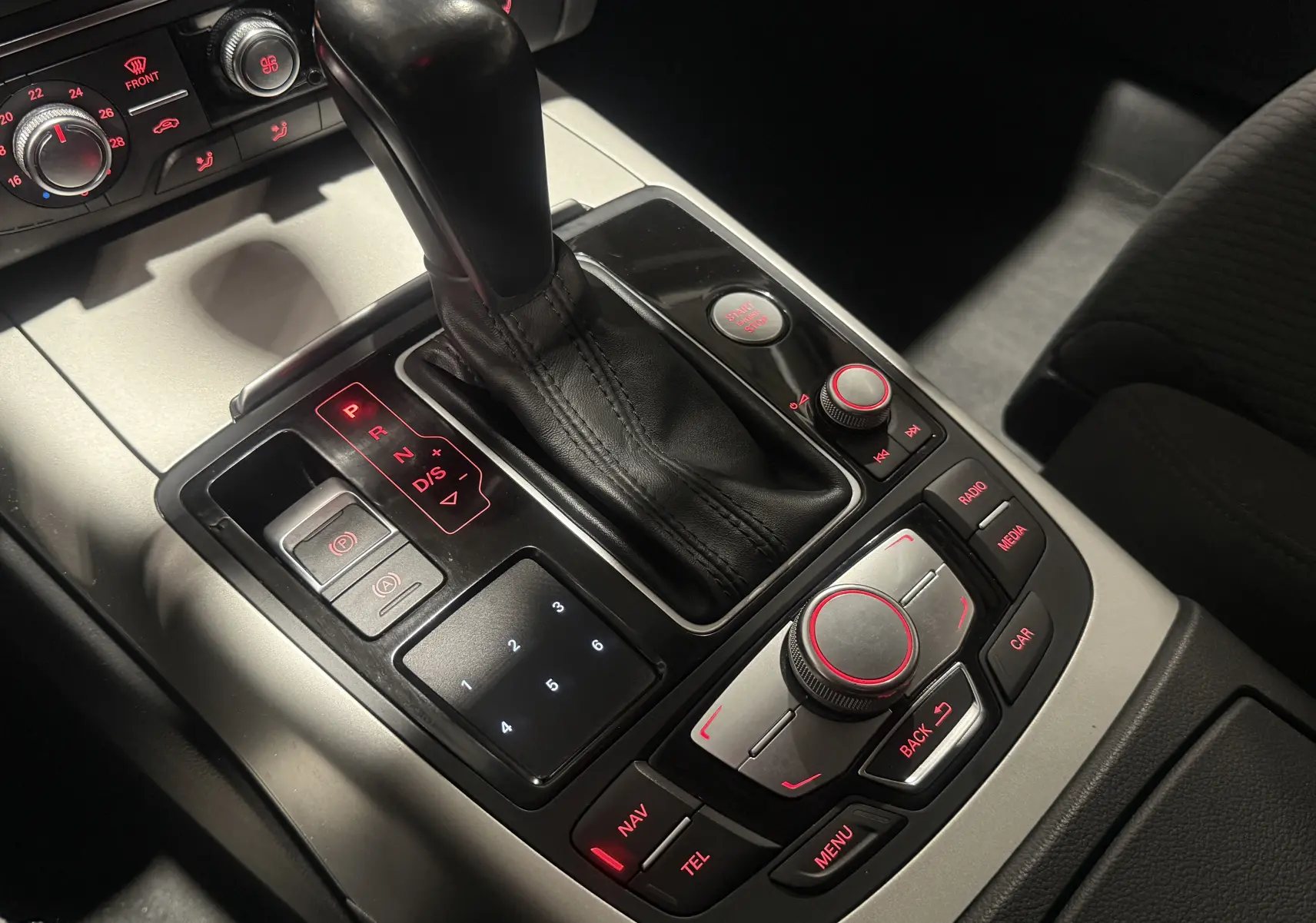 Gros plan sur la console centrale de l'Audi A6 Avant gris 2015, montrant le levier de vitesses automatique et les commandes rétroéclairées.