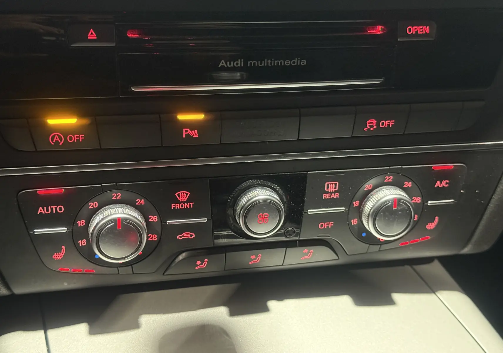 Panneau de commande de la climatisation avec réglages rouges et boutons lumineux dans l'Audi A6 Avant gris 2015.