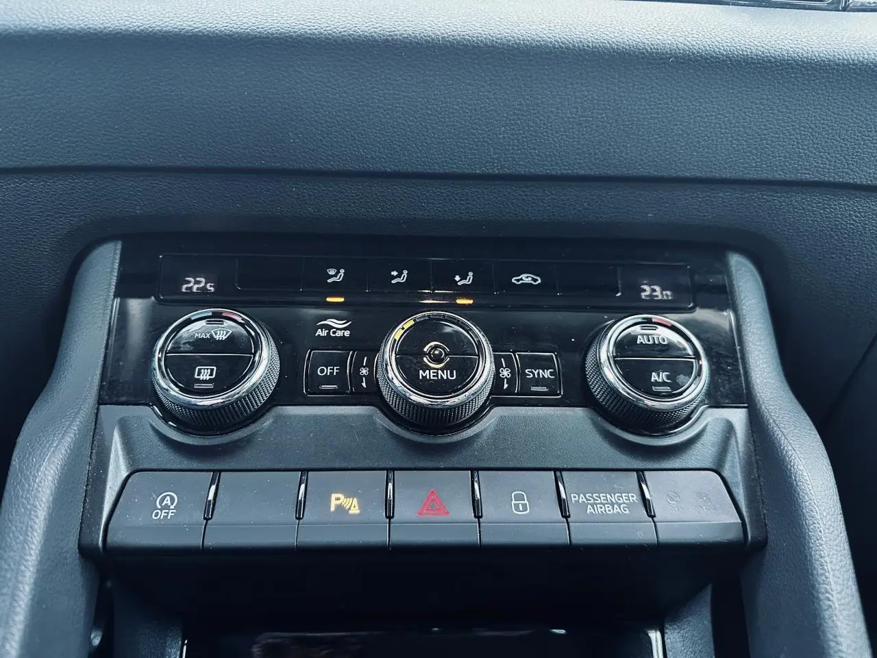 Vue rapprochée de la console centrale noire du Skoda Karoq blanc 2024, avec commandes climatisation et boutons fonctionnels.
