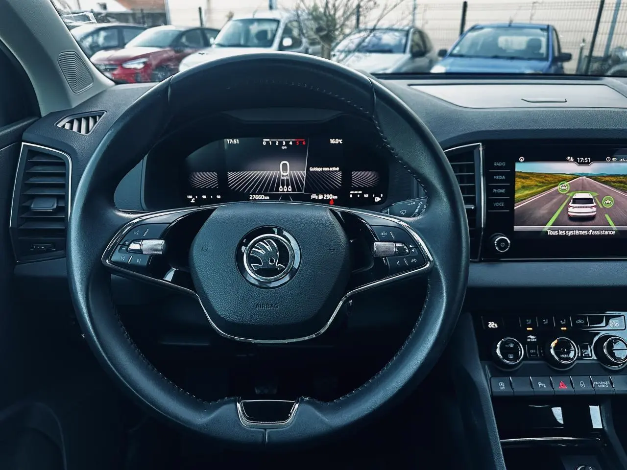 Vue intérieure centrée sur le volant noir du Skoda Karoq 2024 avec tableau de bord digital et écran tactile.