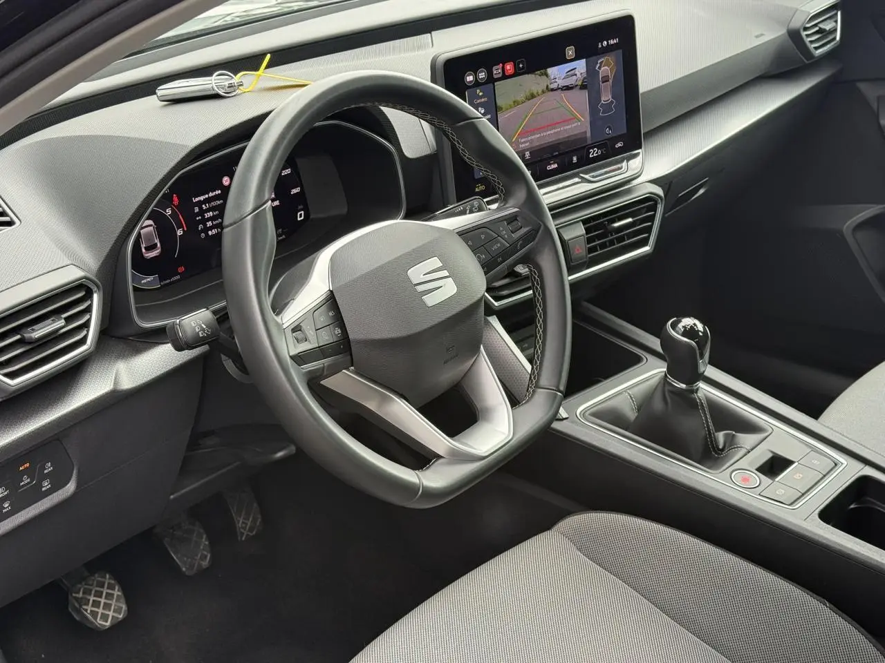 Vue intérieure côté conducteur du SEAT Leon 2.0 TDI noir Minuit, volant cuir multifonction et écran tactile avec caméra de recul.