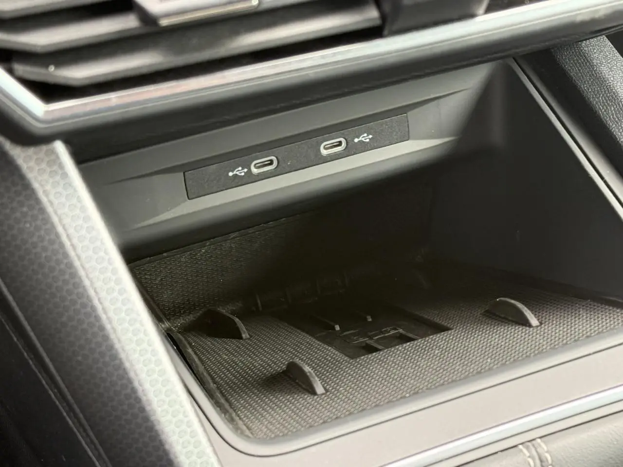 Gros plan sur la connectivité USB-C et le rangement avant du SEAT Leon noir Minuit, intérieur moderne et fonctionnel.