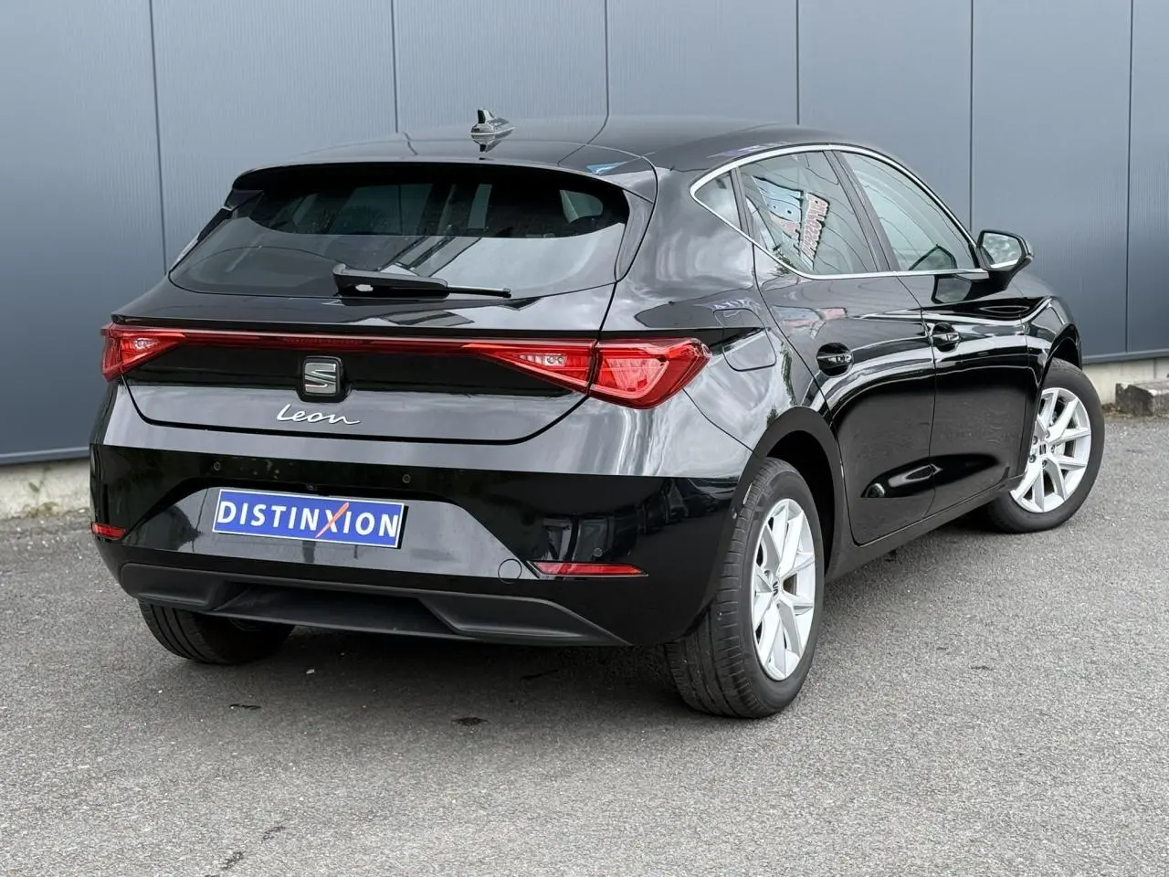 Vue 3/4 arrière droite d'une SEAT Leon noire Minuit avec feux arrière LED et jantes alliage 16 pouces.