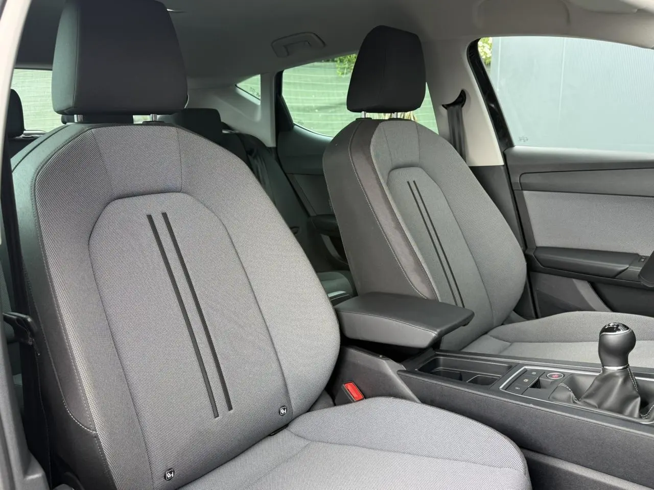 Vue intérieure côté droit des sièges avant gris clair de la SEAT LEON 2025 avec boîte manuelle et accoudoir central noir.