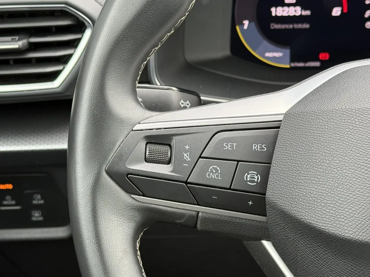 Gros plan sur le volant cuir multifonction côté gauche du SEAT LEON 2.0 TDI 115 Style avec commandes de régulateur.