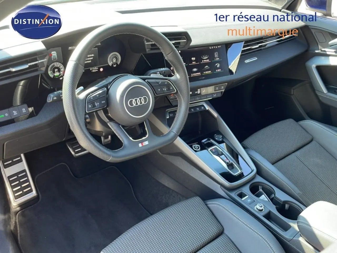 Vue intérieure de l'Audi A3 Sportback 2025, tableau de bord et volant multifonction en cuir noir, console centrale moderne.