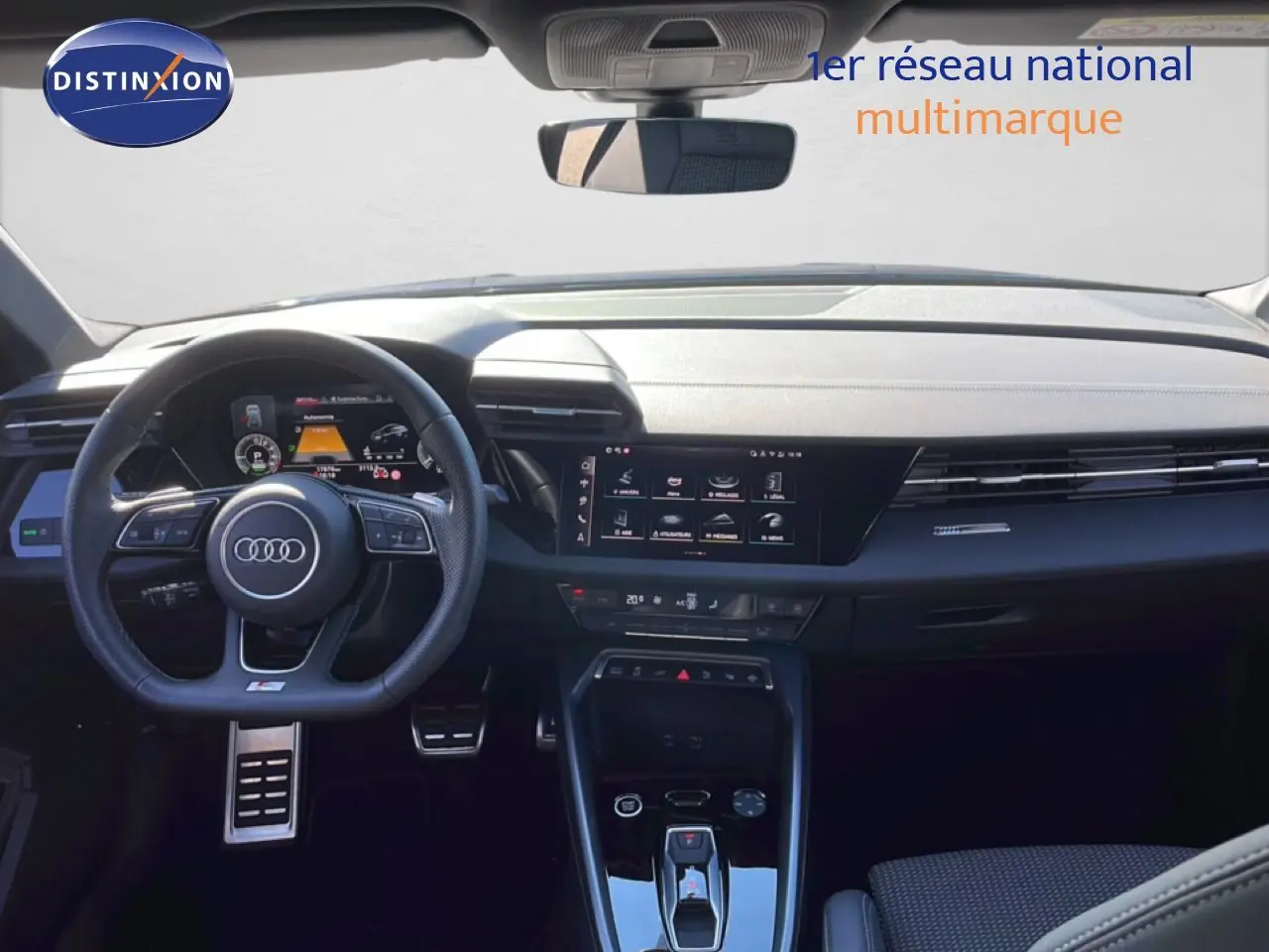 Vue intérieure avant de l'Audi A3 Sportback 2025, tableau de bord noir avec écran tactile et volant multifonction.