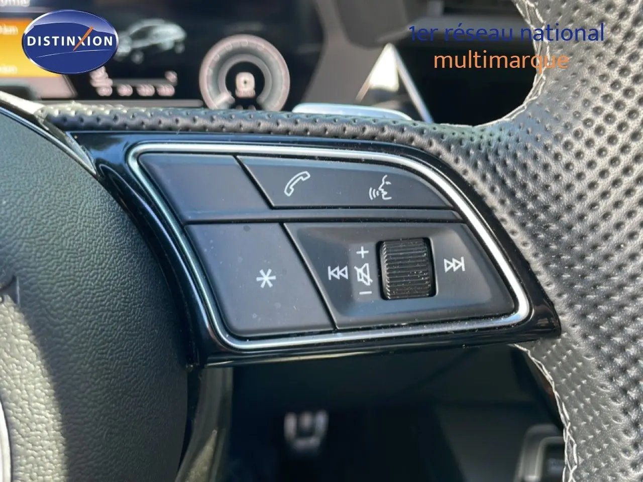 Gros plan sur les commandes de volume et téléphone au volant perforé de l'Audi A3 Sportback bleu Navarre 2025.